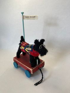 a small toy dog pulling a wooden cart with a sign on it's back