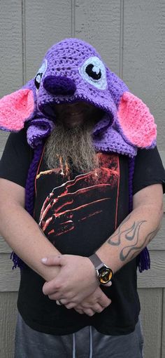 a man wearing a purple crocheted hat with an elephant on it's head