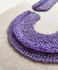 two purple crocheted pieces are laying on the floor next to eachother