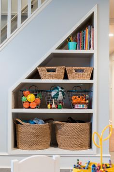 an under the stairs storage area with baskets and toys