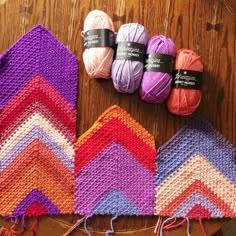 several crocheted items are sitting on a wooden table with yarn in the shape of zigzags