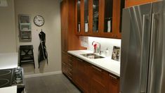 a kitchen with stainless steel appliances and wooden cabinets, along with a clock on the wall