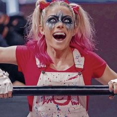 a woman with painted face and makeup holding a metal bar in front of her head