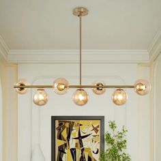 a modern chandelier hangs over a dining room table with chairs and vases