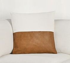 a brown and white pillow sitting on top of a white couch next to a wall