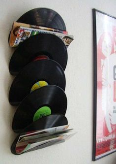 a wall mounted record player next to a magazine rack with vinyl records and magazines on it