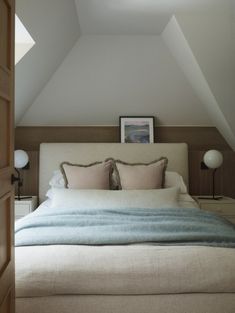 a bed with two pillows on top of it in a bedroom next to an open door