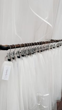 a row of hair brushes hanging on a white curtain with tags attached to the strings