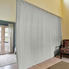 a living room with a chair and a curtain in it's center area, next to a sliding glass door