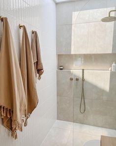 two towels hanging on the wall in a bathroom next to a toilet and shower head