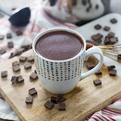 a cup of hot chocolate sitting on top of a wooden cutting board