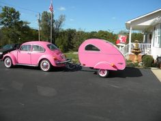 a pink car pulling a trailer in front of a house