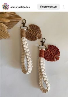 two tasseled key chains hanging on a wall next to a leaf shaped mirror