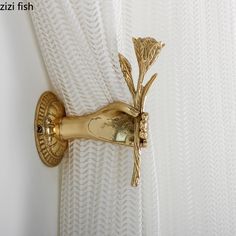 the curtain is gold and has a flower on it's side, hanging from a metal rod