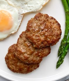 two fried eggs and asparagus on a white plate