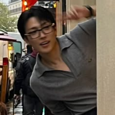 a woman wearing glasses is standing in the street with her hand on her head and people walking by