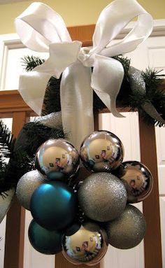 a christmas wreath with ornaments hanging from it's sides and a bow on the front door