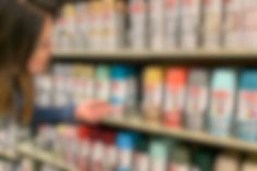 blurry image of people in a store aisle with shelves full of books and drinks