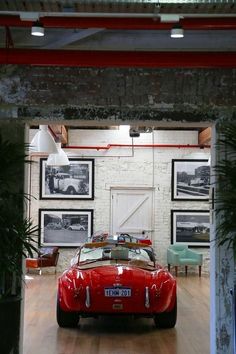 a red sports car is parked in a garage with pictures on the wall behind it