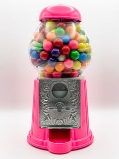 a pink gummy machine filled with lots of colorful candies in front of a white background