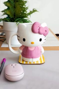 a hello kitty mug sitting on top of a desk next to a mouse