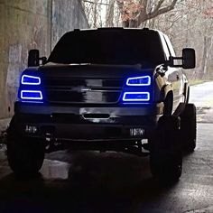 the front end of a black truck with blue lights on it's grilles