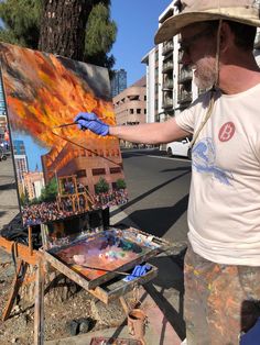 a man is painting on an easel with flames in the air and words above it