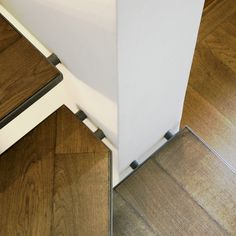 the bottom half of a white refrigerator with wood flooring on it's side