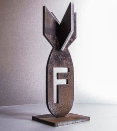 a metal sculpture with the letter f on it's base, sitting on a table