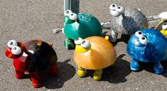 five colorfully painted plastic animals standing next to each other on the ground in front of a pole