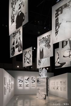 an art gallery with black and white artwork hanging from the ceiling