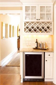 a kitchen with white cabinets and wood flooring next to a wine rack on the wall