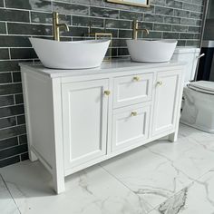 two white sinks sitting next to each other on top of a marble counter in a bathroom