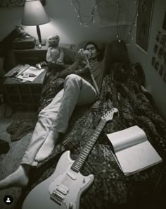 a man laying on top of a bed next to a guitar