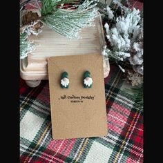 a pair of green and white earrings sitting on top of a card