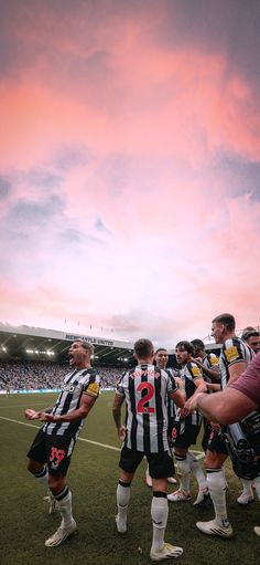 a group of men standing on top of a soccer field next to each other under a cloudy sky