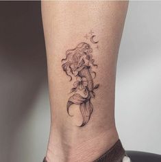 a woman's leg with a tattoo on it that has a mermaid sitting on top of a fish