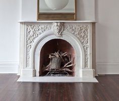 a white fireplace with a mirror above it