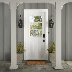 a white door with two planters on either side and an entrance mat in front