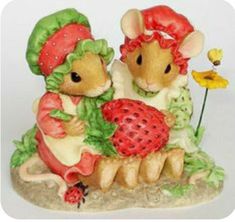 two little mice are hugging each other with strawberries on the ground next to them