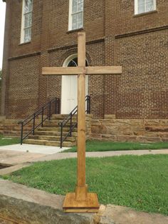 a wooden cross sitting in front of a brick building with steps leading up to it