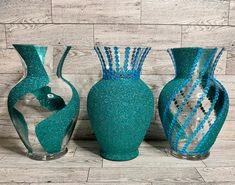 three green vases sitting on top of a wooden floor next to each other in front of a wall