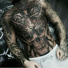 a man with tattoos on his chest has a tiger and skull tattoo on his back