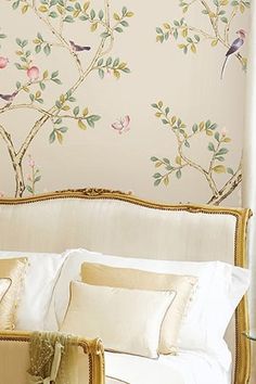 a bed with white sheets and pillows in front of a wallpapered headboard