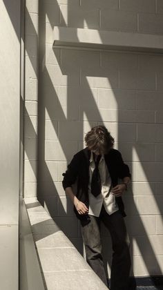 a man standing in front of a white brick wall