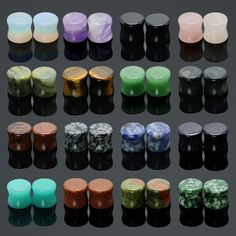 many different colored candles are arranged on a black surface, with one candle in the middle