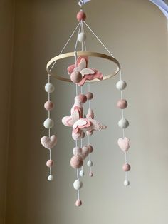 a pink and white mobile with hearts hanging from it's sides in a room