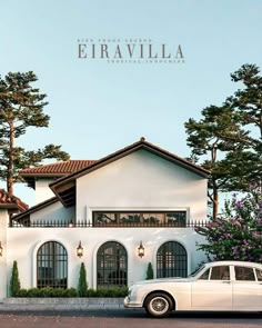 a white car is parked in front of a house with trees and bushes on the side