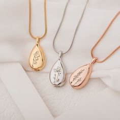 three necklaces with different designs on them sitting next to each other in gold, silver and rose gold