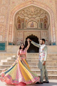 a man and woman standing in front of a building holding each other's hands